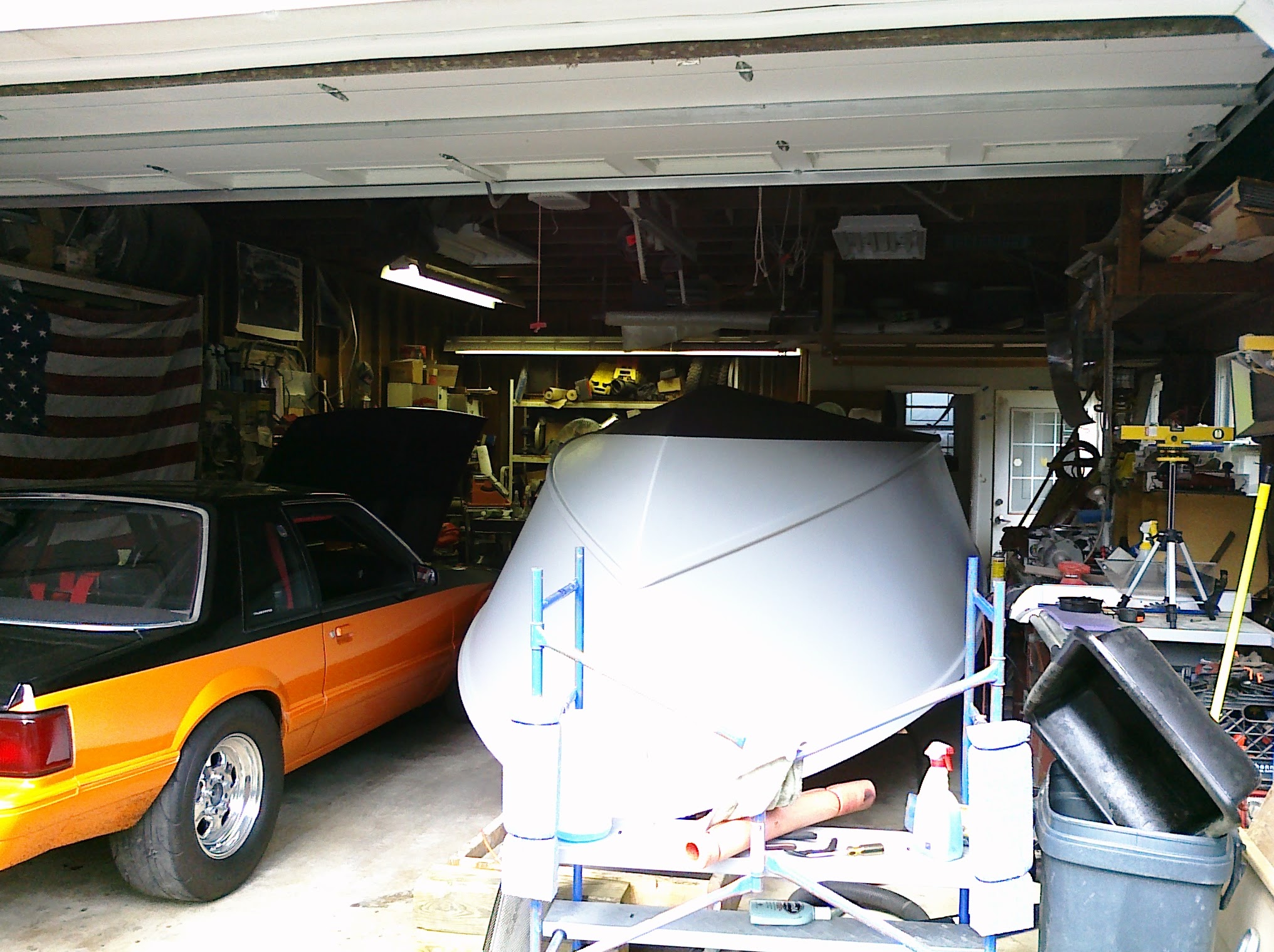 Orange 88 Mustang and gray J-Marie hull together in garage