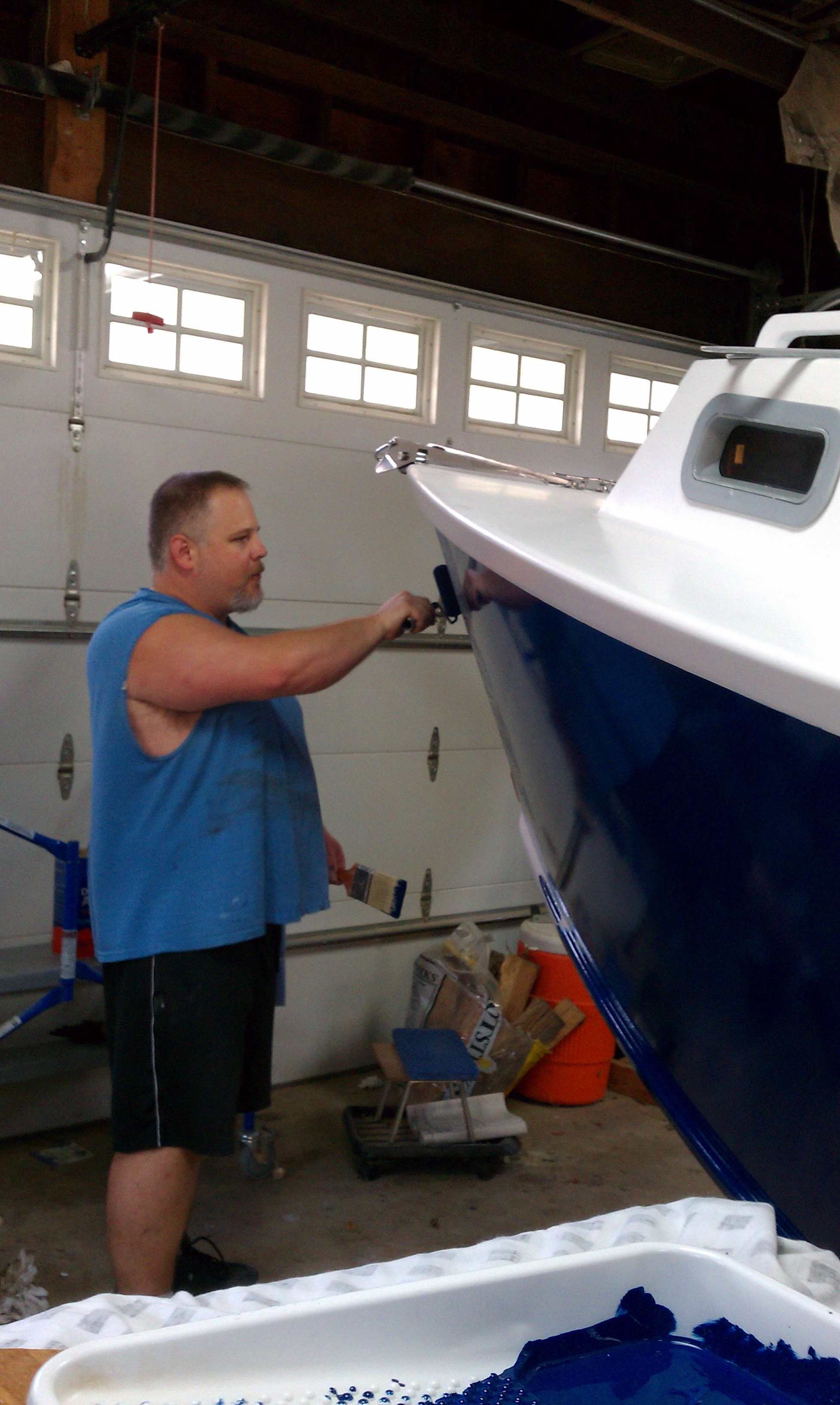 Lane rolling navy blue paint onto the hull