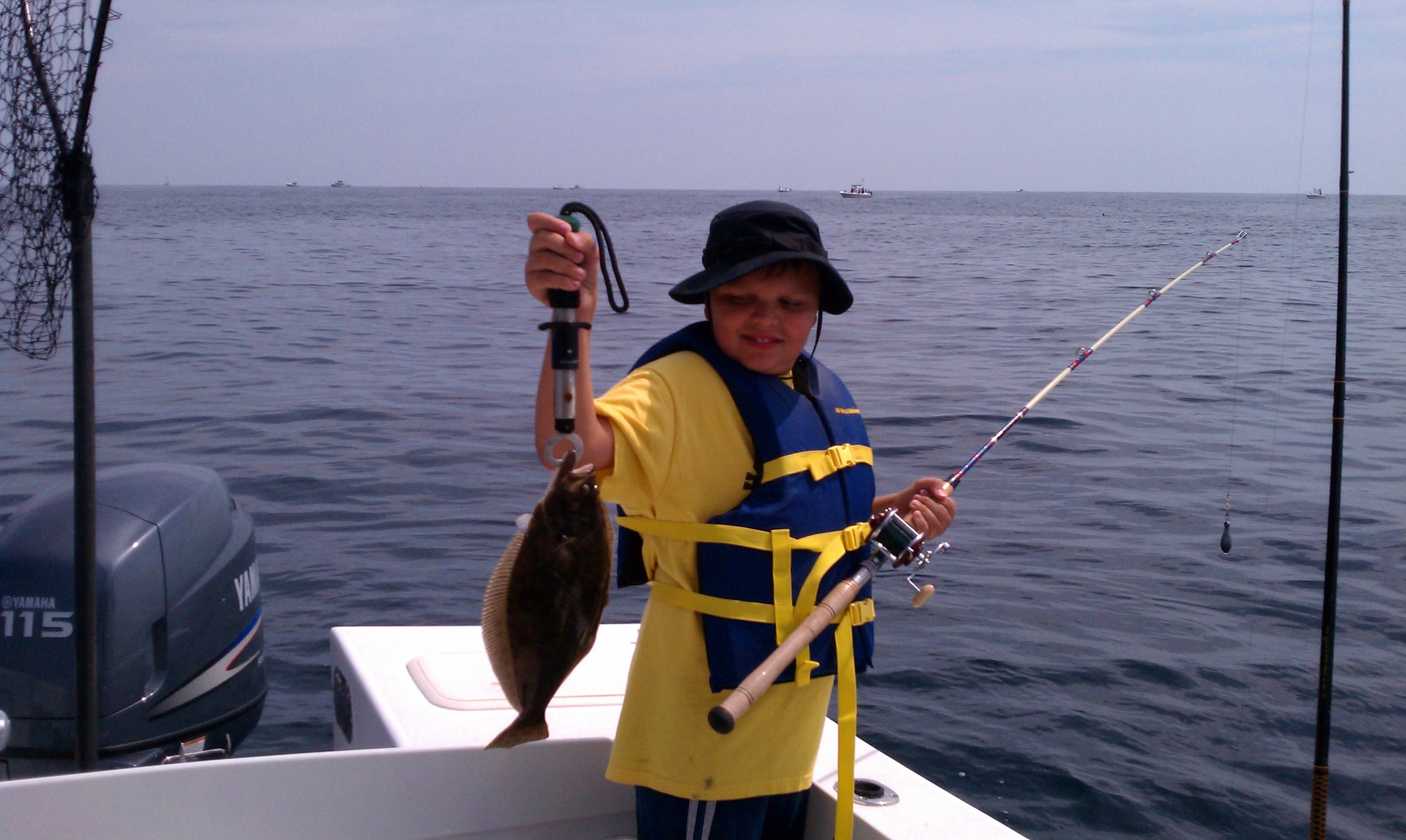 Young Dominic holding a fluke on the boat