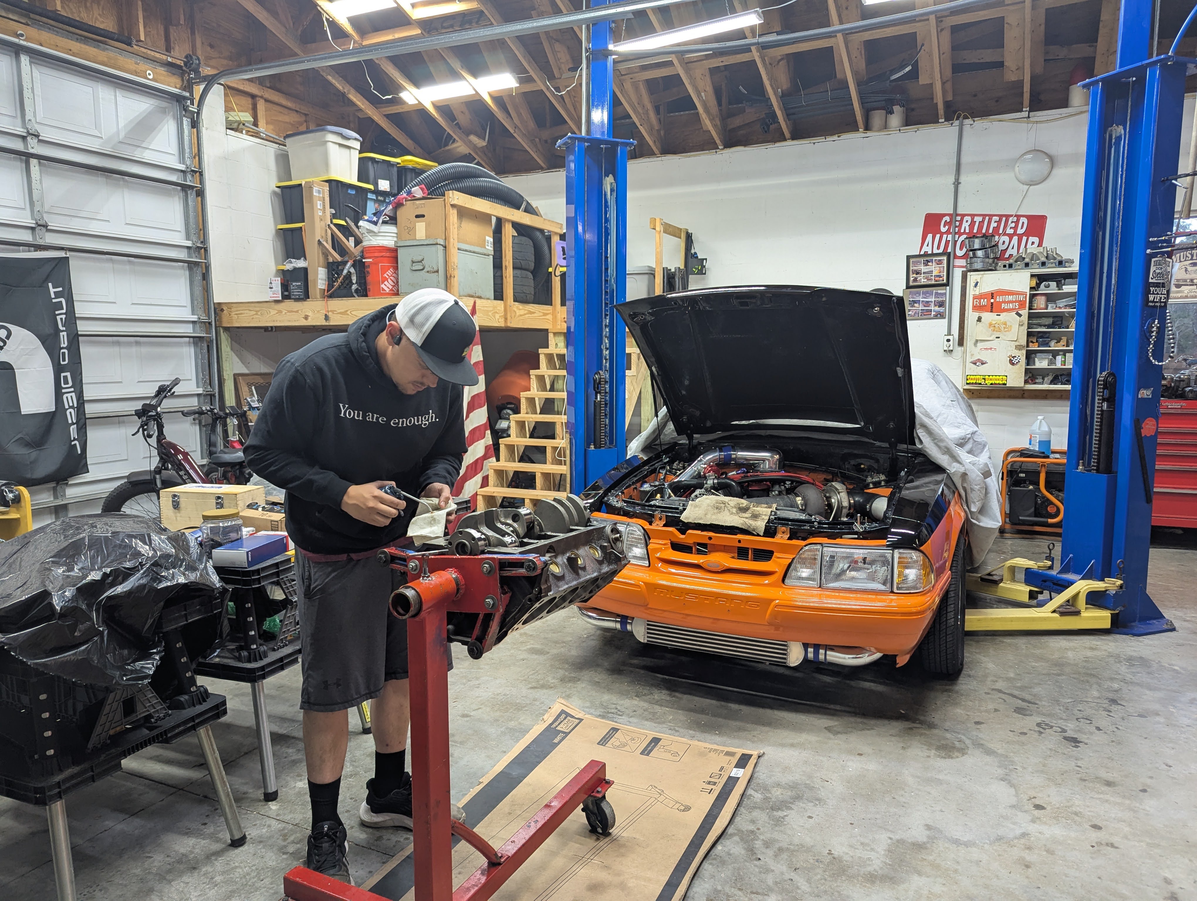 Dominic working on engine stand, orange 88 on lift behind