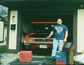 A young Lane Palmer standing in front of the garage with the finished red 1973 Grande behind him