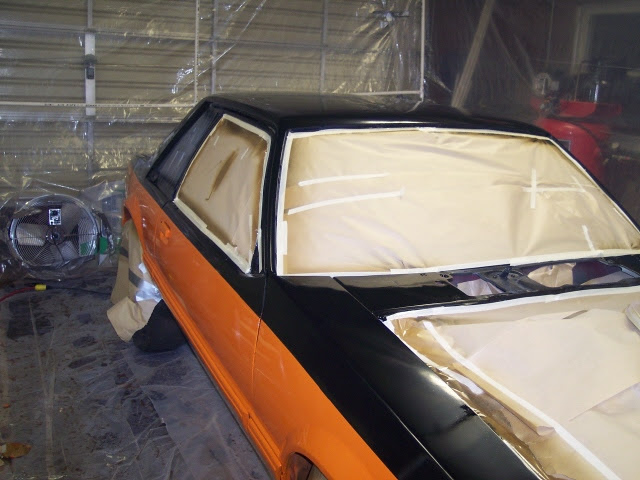 Car in paint booth, orange and black, nearly finished